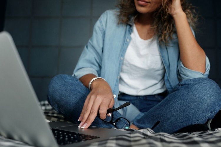 A woman wearing jeans sit in front of laptop