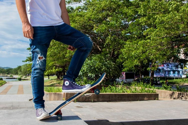 man wear jeans while using skateboard