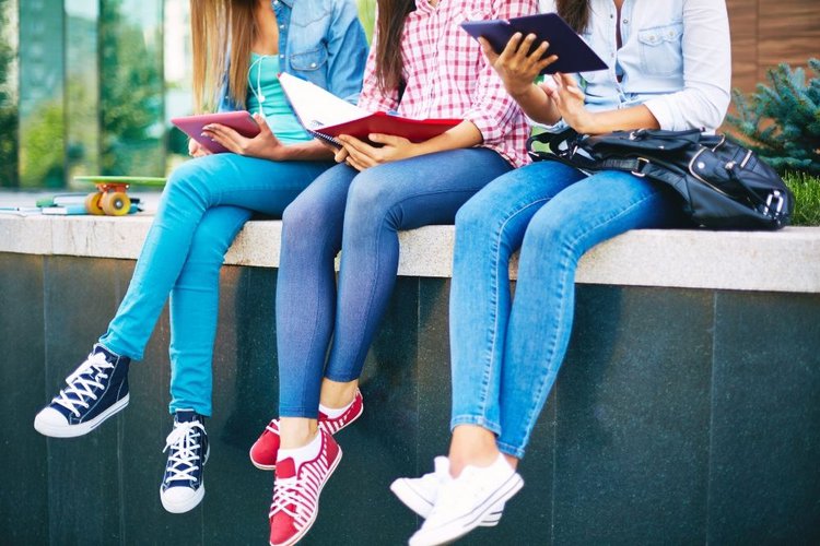 three girls wearing jeans reading books