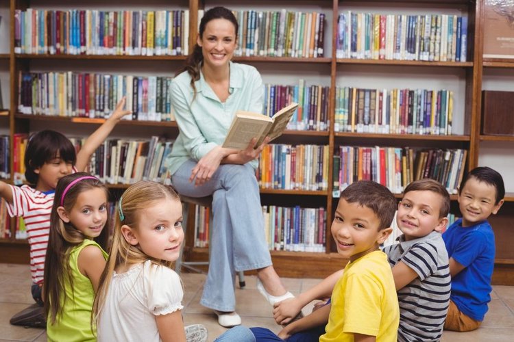female teacher holding a book teaching six kids