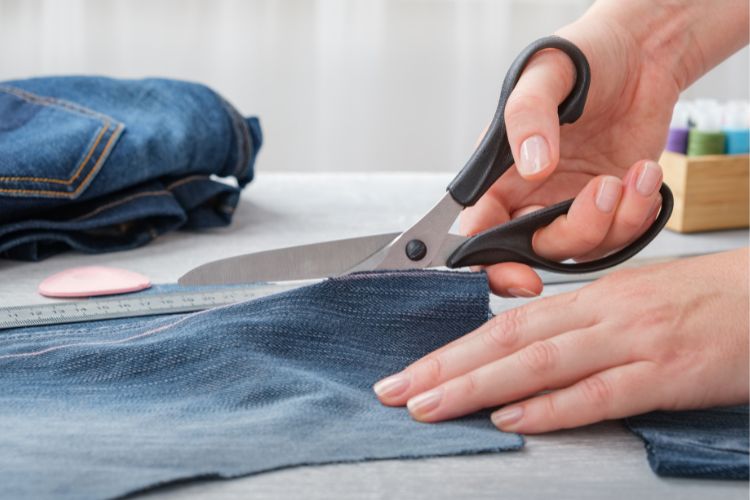a tailor is cutting denim fabric