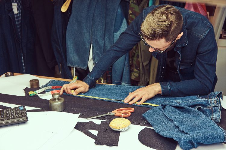 a tailor measures the legs of jeans