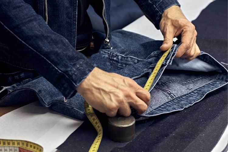 a tailor measures the waist of jeans