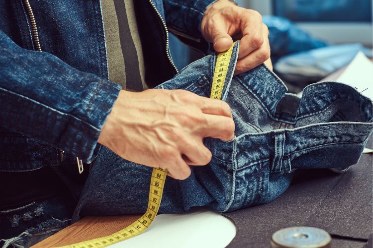 a tailor measures the waistband of jeans