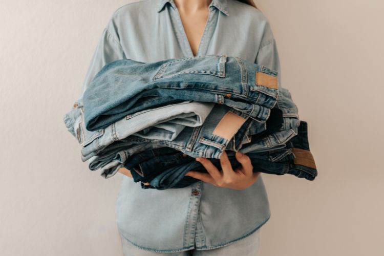 woman holds a bunch of jeans