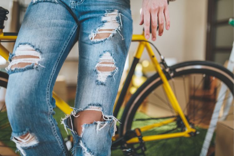 a person wears ripped jeans sitting on a bicycle