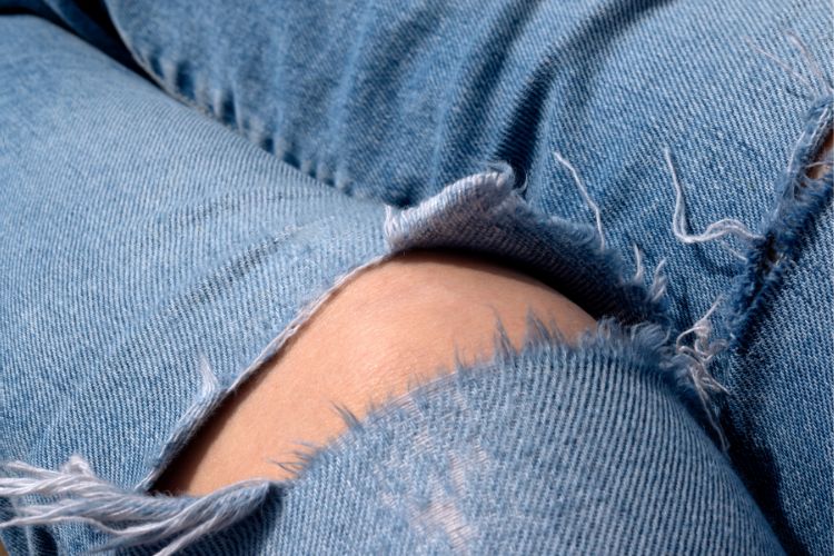 frayed threads and knees of a girl wearing ripped jeans