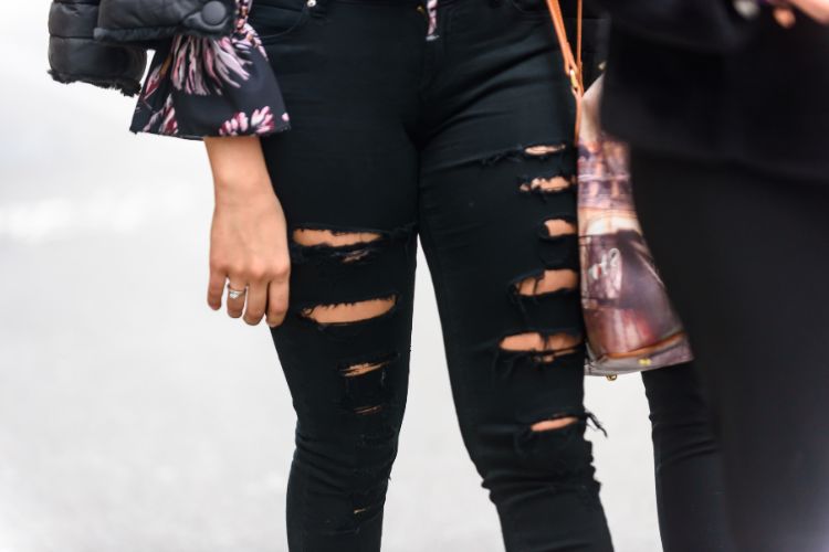 girl wears black ripped jeans with many tears