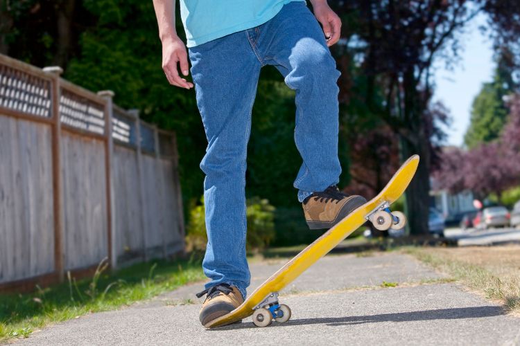 man wearing jeans is riding a skateboard