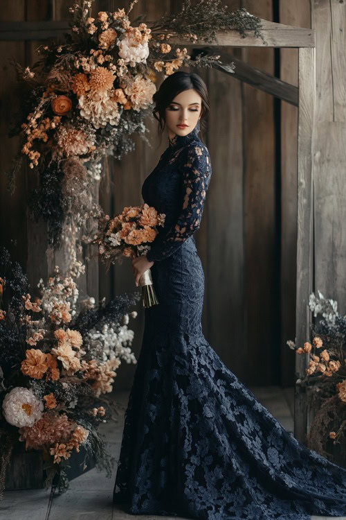 A fashionable woman in a navy floor-length gown with intricate lace detailing, posing near an indoor floral wedding arch decorated with winter blooms (2)