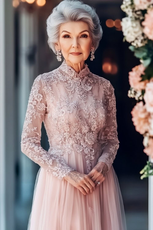 A fashionable woman over 50 in a blush pink cocktail dress with floral lace details, standing near a grand wedding entrance decorated with flowers