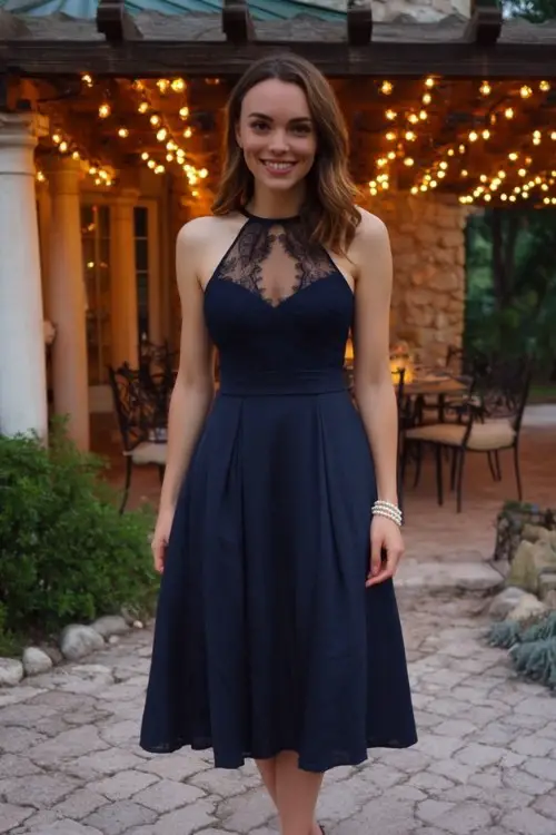A petite woman wears a navy fit-and-flare midi dress with an illusion mesh neckline and lace detailing