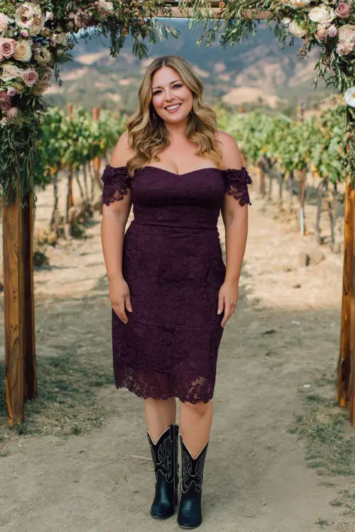 A plus-size woman over 40 wears a deep plum off-the-shoulder midi dress with embroidered details and classic black cowboy boots