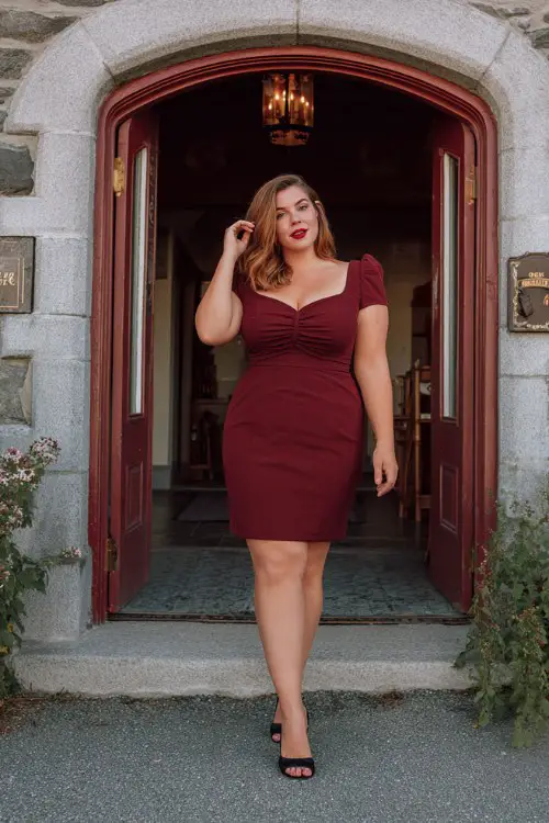 A plus-size woman wears a dark red tailored short dress with a square neckline and black heels