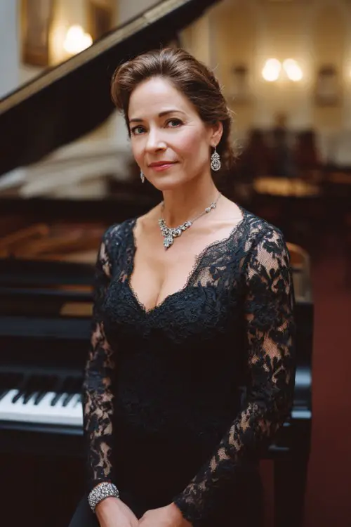 A woman over 40 wears a long-sleeve black gown with lace detailing and silver accessories