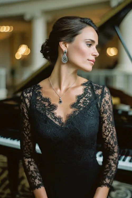 A woman over 40 wears a long-sleeve black gown with lace detailing and silver accessories