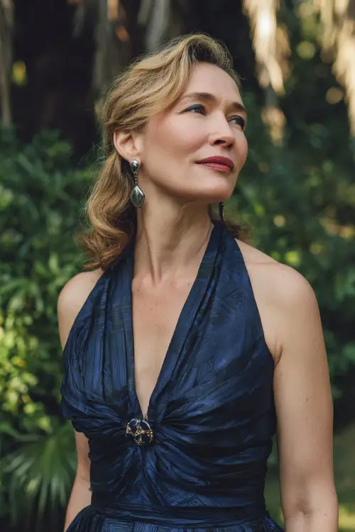 A woman over 50 wears a rich navy gown with a pleated bodice and tonal geometric jacquard pattern