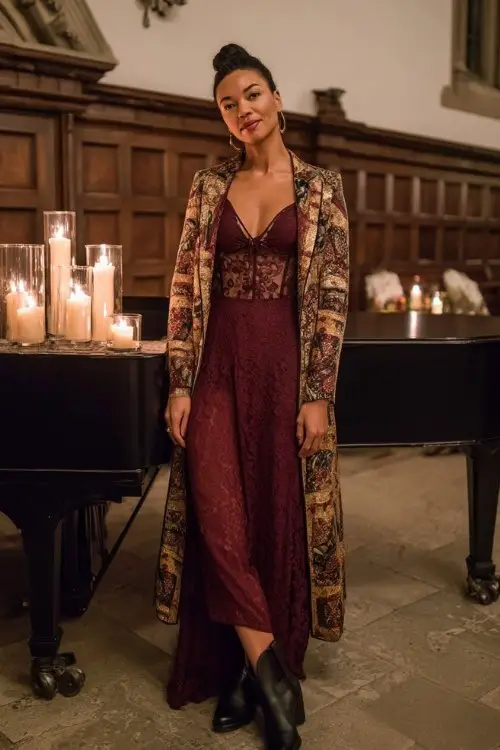 A woman wears a burgundy lace gown with sheer sleeves, a patterned jacquard coat in gold tones, and black cowboy boots (2)