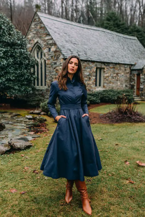 A woman wears a navy blue fit-and-flare midi dress, layered with a cropped quilted jacket and tan leather boots (2)