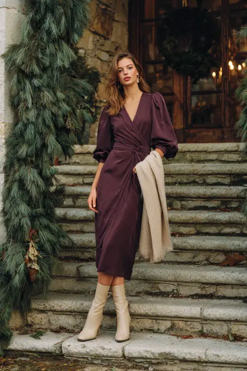 A woman wears a plum chiffon midi dress with puff sleeves, a beige wool wrap, and heeled boots