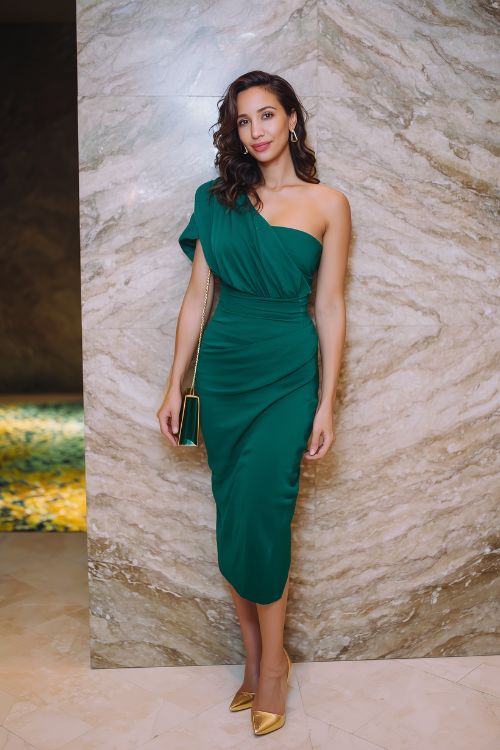 a woman wears a green one shoulder midi dress with gold heels