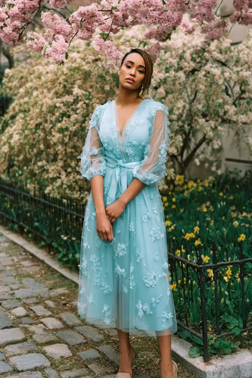 A plus-size woman wears a baby blue tulle dress with 3D floral appliqué and a belted waist