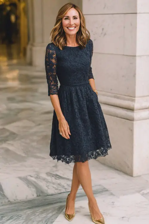 A woman over 40 wears a navy cocktail dress with a lace overlay, three-quarter sleeves, and a flattering tulip skirt, paired with gold kitten heels