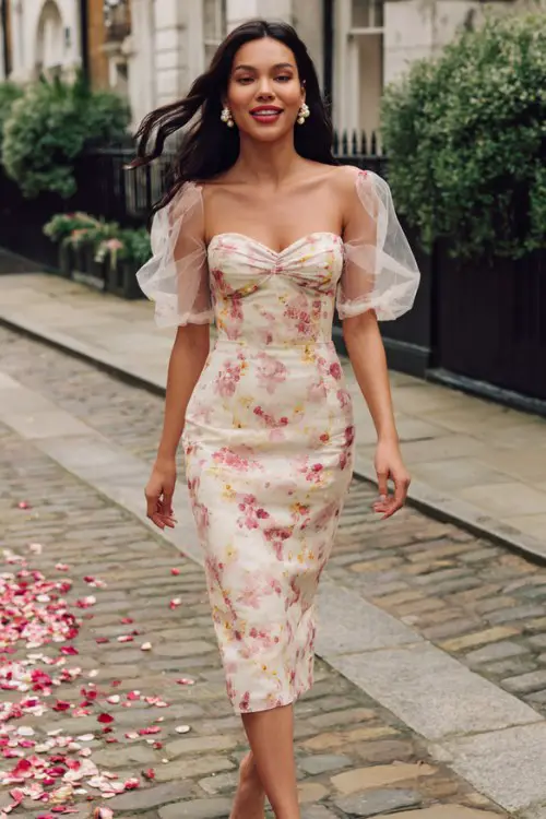 A woman wears a cream floral-printed organza midi dress with a sweetheart neckline and puff sleeves, styled with pearl earrings and block heels