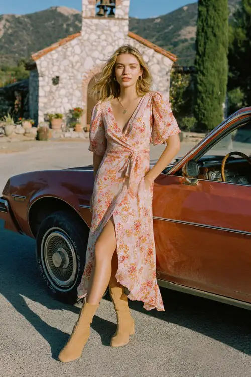 A woman wears a peach floral wrap dress with a high-low hem and sleek tan sock boots