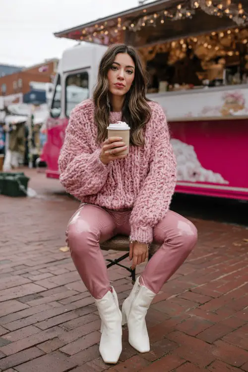 A woman wears a pink oversized knit sweater with faux leather leggings and white ankle boots (2)