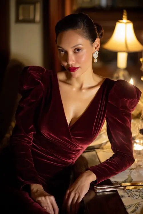 Sophisticated old money woman at an upscale dinner wearing a deep red velvet midi dress with puff sleeves, tailored waist, elegant evening look