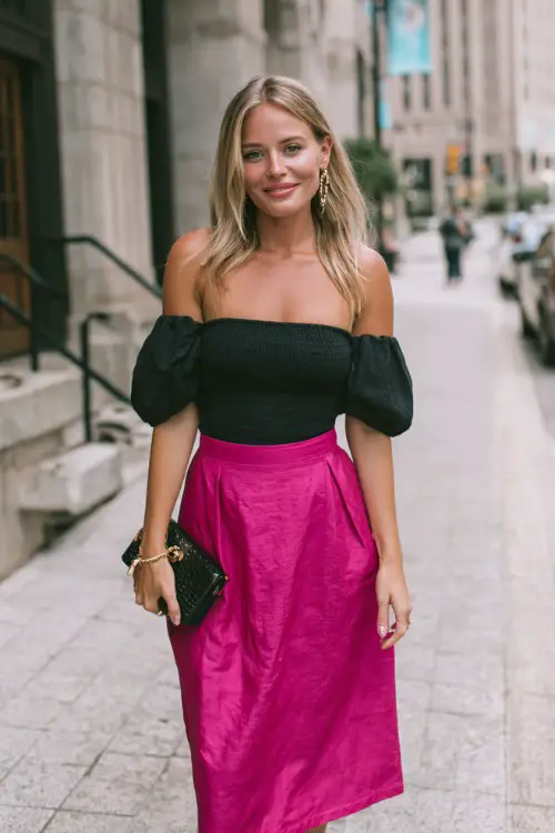 a woman wears a black off shoulder top with fuchsia pink midi skirt for a date night