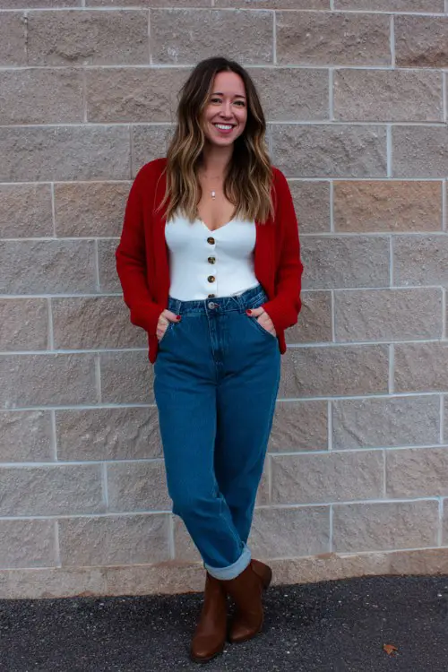 a woman wears a red cardigan over a white top, blue jeans and brown boots for a date night