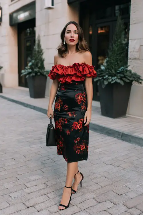 a woman wears a ruffle top with black midi skirt with red floral patterns for date night
