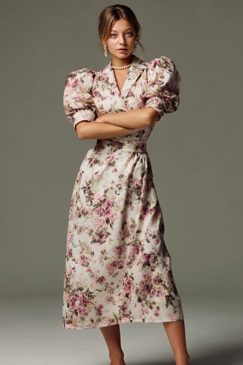 Chic woman wearing a floral print tea-length dress with puff sleeves and delicate pearl studs, posing in a luxury studio with a pale gray backdrop 