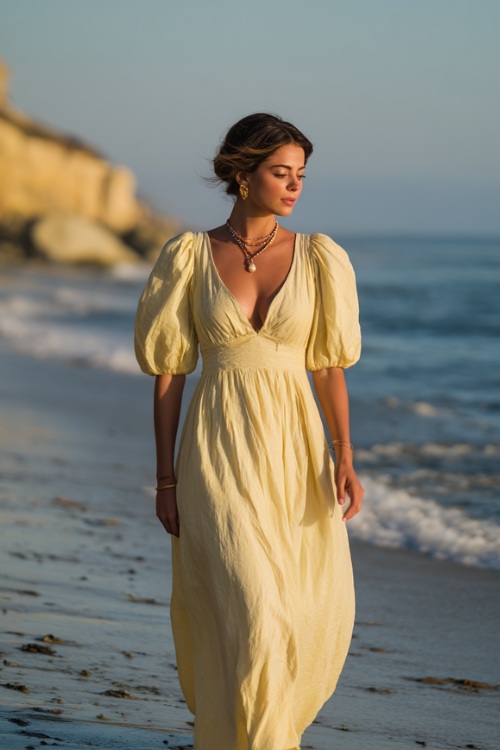 Sophisticated lady in a pale yellow flowy maxi dress with puff sleeves and subtle jewelry, strolling gracefully on the shoreline under soft golden light