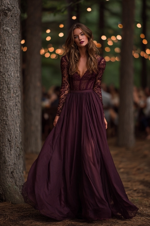 Woman in a plum-toned gown with lace long sleeves, fitted bodice, and flowing skirt, standing under a string-lit tree canopy at a romantic outdoor ceremony 