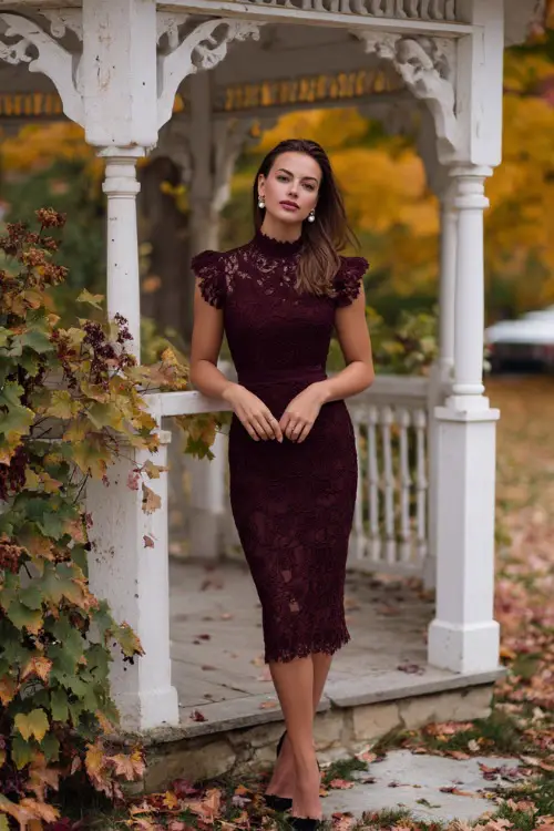 Woman wearing a burgundy lace midi dress with scalloped edges and cap sleeves, accessorized with pearl drop earrings and black heels 