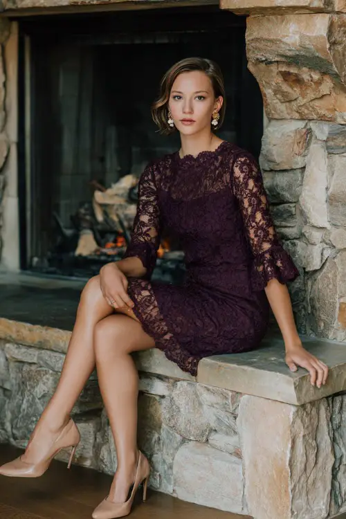 Woman wearing a plum lace sheath dress with scalloped edges and three-quarter sleeves, accessorized with pearl earrings and beige pumps