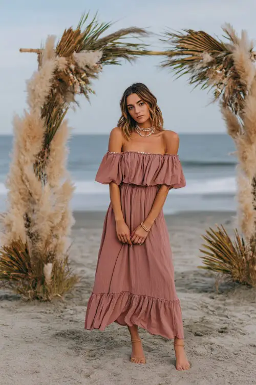 A woman wears a dusty rose off-the-shoulder maxi dress with a ruffled hem, paired with delicate sandals and seashell jewelry