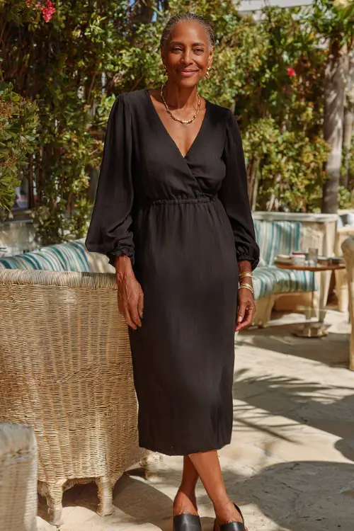 A Black woman over 50 in a relaxed midi dress with long sleeves