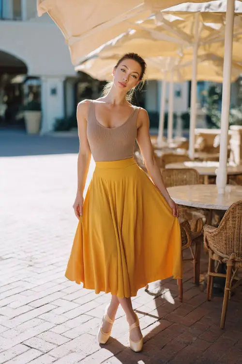 A woman in ballet flats paired with a flowy midi skirt and a fitted knit top, accessorized with minimal jewelry, posing in a bright outdoor brunch setting