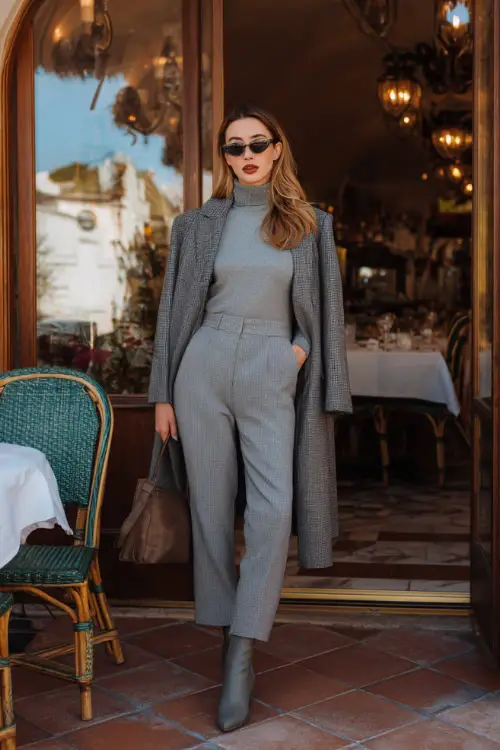 A woman in straight-leg trousers paired with a soft turtleneck and a wrap coat, styled with ankle boots and a leather handbag