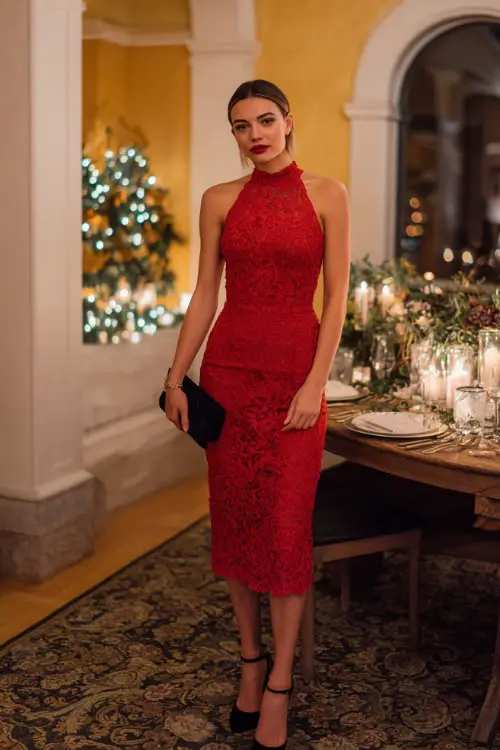 A woman wears a red lace midi dress, black heels, and a small clutch, standing full body in a decorated holiday dinner party setting with soft candle glow