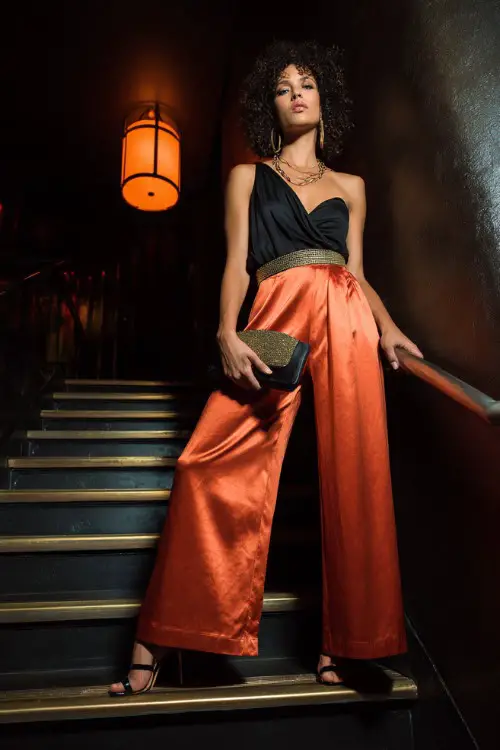 A glamorous woman wearing metallic wide-leg pants with a bold asymmetrical top and sleek high heels 