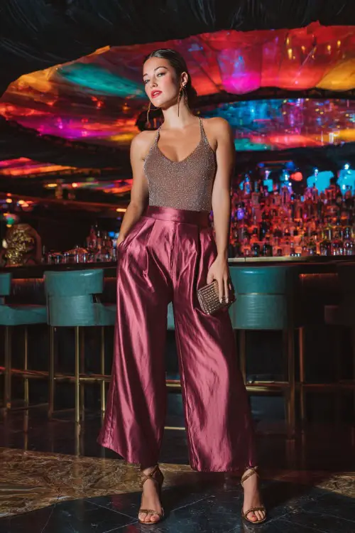 A glamorous woman wearing sleek satin wide-leg pants with a sparkly sleeveless top and strappy heels