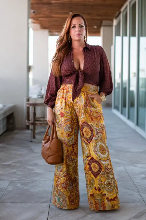 A plus-size woman over 40 wears a boho chic outfit with a fitted blouse tucked into wide-leg pants