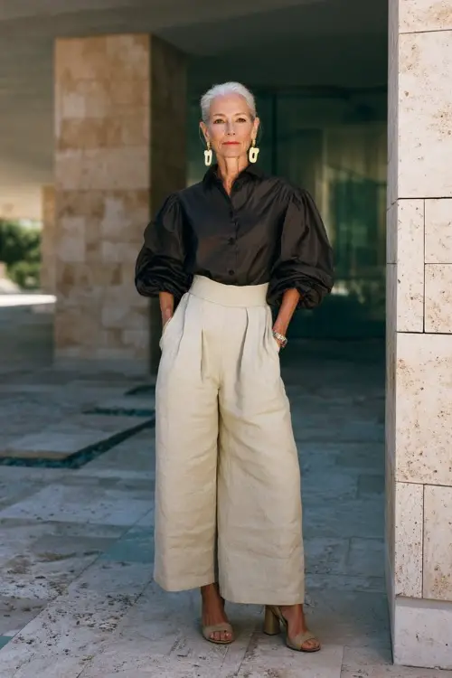 A woman over 50 wears a boho chic outfit with a structured blouse and wide-leg linen pants