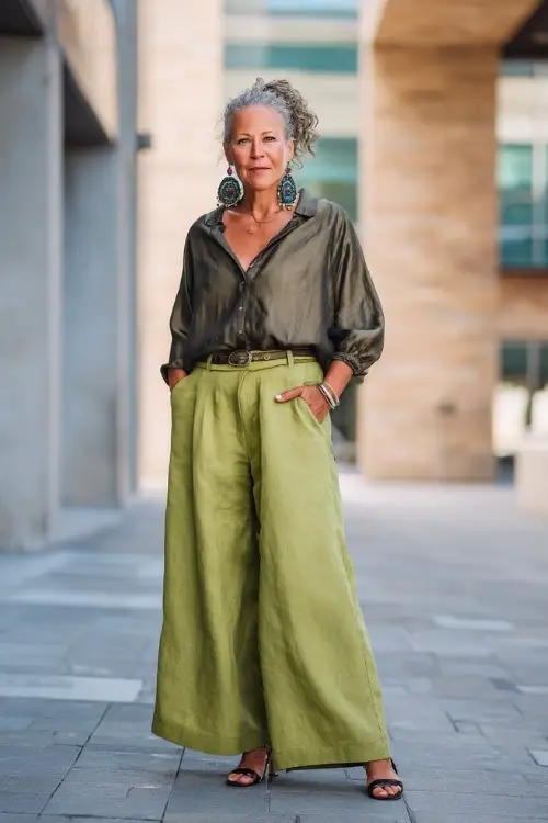 A woman over 60 wears a boho chic outfit with a structured blouse and wide-leg linen pants 