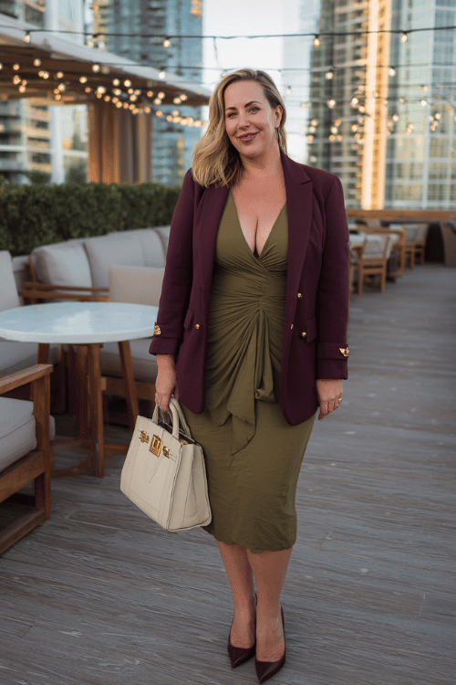 a plus-size woman over 50 wearing a sophisticated olive green midi wrap dress with a deep V-neckline and long flowing sleeves, layered with a tailored burgundy blazer